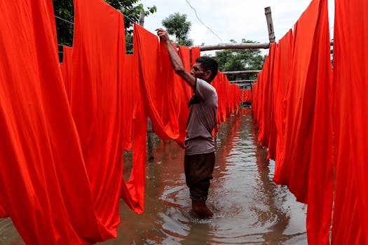 Man drying red fabric outdoors in Narayanganj, Bangladesh.