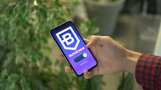 Close-up of a smartphone showing a blockchain app screen held by a hand.